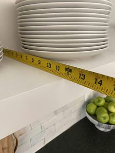 there is a measuring tape next to some green apples in a bowl on the counter