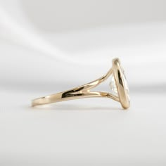 a yellow gold ring with a white diamond in the center on a white background,