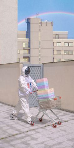 an astronaut pushing a shopping cart with a rainbow in the background