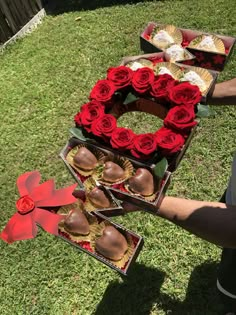 a man holding two trays of chocolate covered strawberries with roses in the middle