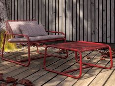 two chairs and a coffee table sitting on a wooden deck next to a tree with leaves around it