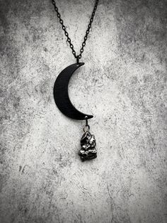 a black and white photo of a necklace with a skull on the moon hanging from it's side