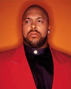 a man in a red jacket and black shirt is looking at the camera with an intense look on his face