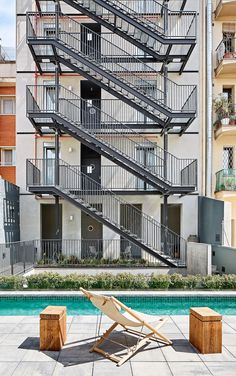 a white chair sitting on top of a cement floor next to a swimming pool in front of a tall building