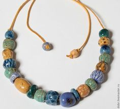 a necklace and earring made out of glass beads on a white surface with a cord