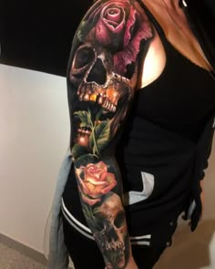 a woman with a tattoo on her arm and shoulder is holding a rose in front of a skull