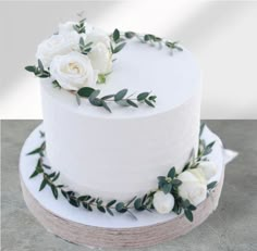 a white wedding cake with flowers and greenery on the top is ready to be cut