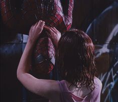 a woman standing in front of a spider man statue with her hands on the face