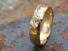 a gold wedding ring sitting on top of a cement surface with rusted paint all over it