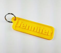 a yellow key chain with the word jenny written in large letters on it, sitting on a white surface