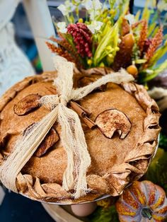 a person holding up a pie on top of a plate with flowers in the background