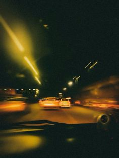 cars driving down the road at night with street lights in the background and blurry image