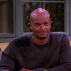 a bald man sitting at a table with a plate of food in front of him