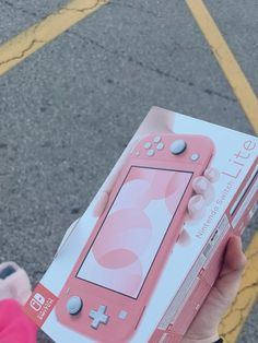 a person holding up a pink nintendo lite game controller in their left hand, with the box open