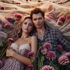 a man and woman laying on top of flowers