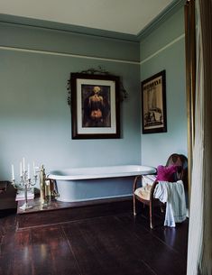 a bathroom with a tub, chair and pictures on the wall