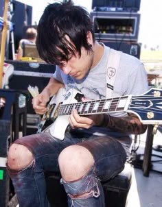 a man sitting down playing an electric guitar