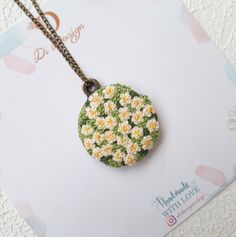 a necklace with daisies on it sitting on top of a piece of paper