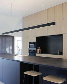 an empty kitchen with two stools in front of the counter and cabinets on the wall