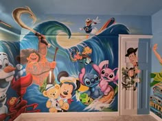 this is a bathroom decorated with cartoon characters on the wall and in the shower area