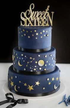 a three tiered blue cake with stars and moon decorations on top, sitting on a table