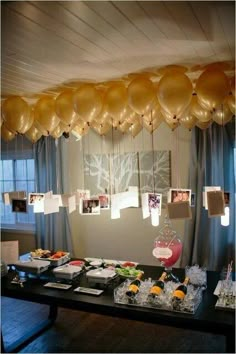 balloons are hanging from the ceiling above a table with food and drinks on it,