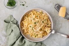 a white bowl filled with pasta and parmesan cheese on top of a table