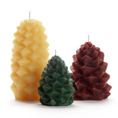 three pine cone candles sitting next to each other