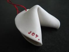 an ornament with the word joy written on it and two pieces of red string