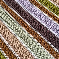 a multicolored crocheted blanket is laying on top of a tablecloth