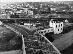 black and white photograph of an old town with railroad tracks in the foreground, buildings on either side