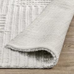 a white rug on top of a wooden floor next to a wood flooring area