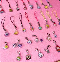 a pink table topped with lots of cartoon keychains and lanyards covered in charms