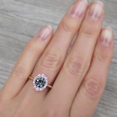 a woman's hand with a diamond ring on top of her finger and wood floor in the background