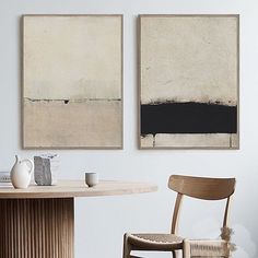 two paintings hang on the wall above a table