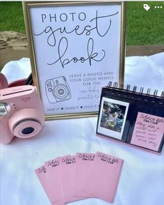 a table topped with pink cards and a camera next to a sign that says photo guest book