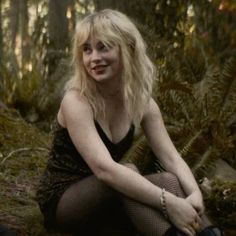 a woman is sitting in the woods with her legs crossed and wearing fishnet stockings