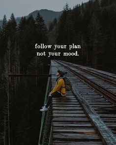 a person sitting on a train track with the words follow your plan not your mood