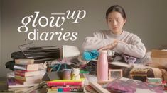 a woman sitting in front of a pile of books with the words glow up diaries on it