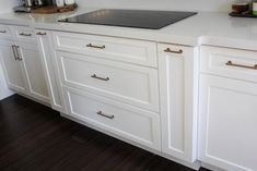 a kitchen with white cabinets and wood flooring is seen in this image from the front view