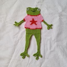 a crocheted frog with a pink shirt and star on it's chest