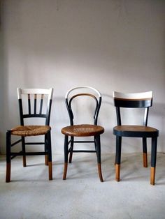 three wooden chairs sitting next to each other in front of a white wall and floor