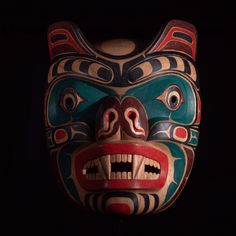 a wooden mask with an elaborate design on it's face and mouth, in the dark