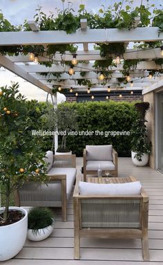 an outdoor living area with white furniture and potted plants