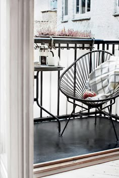 a white chair sitting on top of a balcony next to a black iron table and chairs