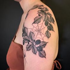 a woman's shoulder with leaves and flowers on her left arm, in black and white