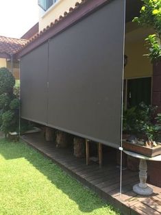 an outdoor area with green grass and plants on the side of the house, covered by a motorized screen