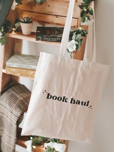 This beautiful bookish tote bag is perfect for any book lover! Great for carrying your current read, or reads, and for a book shopping spree! The text reads: 'Book Haul' The tote bag is made from cotton with handles, and a vinyl design on the front.  Measures approx: 40 x 37cm (excluding handles) Care instructions: - Wash inside out at 30 degrees with similar colours, or by hand. - Iron using lower heat setting, inside out. - Do not tumble dry. Please do get in touch with any questions, and we w Book Shopping, Book Haul, Thanks For The Gift, Book Storage, The Tote Bag, Bookish Gifts, Business Events, Gifts For Readers