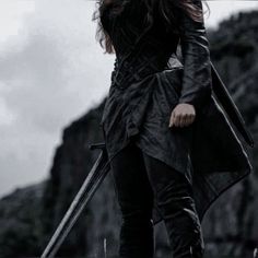 a woman with long hair standing on top of a mountain holding two swords in her hand