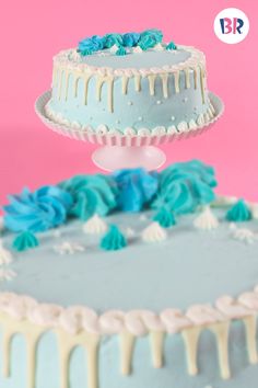 a blue and white cake with icing drizzled around it on a pink background